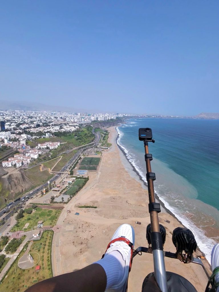 Beyond Barriers travel: paragliding above the Lima coastline in Peru, looking down on the beach and the Pacific surf